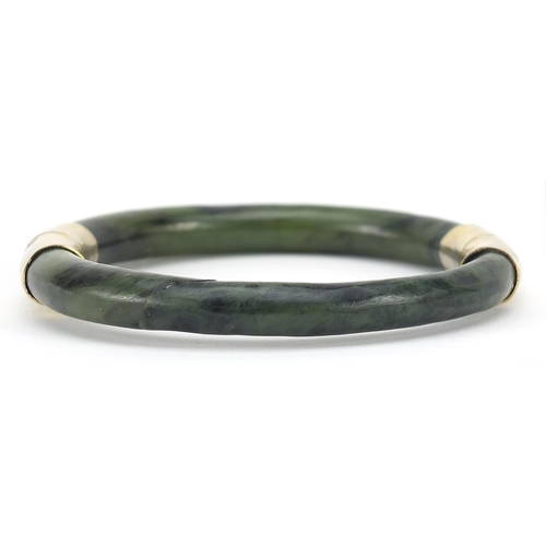 950 - Chinese green jade bangle with gilt metal mounts, 7.5cm in diameter, 38.0g