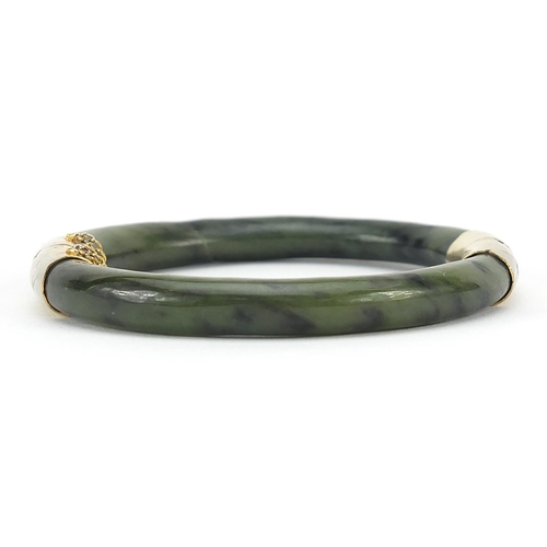 950 - Chinese green jade bangle with gilt metal mounts, 7.5cm in diameter, 38.0g