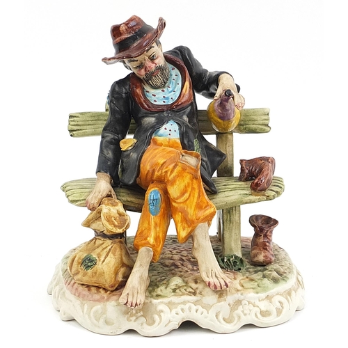 20 - Hand painted Capodimonte figure of a tramp on a bench, 26cm high