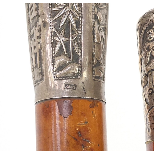 941 - Two malacca walking sticks with Chinese silver pommels embossed with figures and calligraphy, the la... 