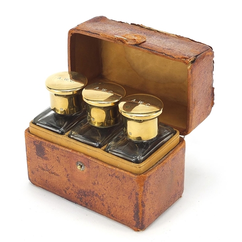 876 - Three 19th century cut glass bottles with brass lids housed in a fitted leather travelling case, ove... 