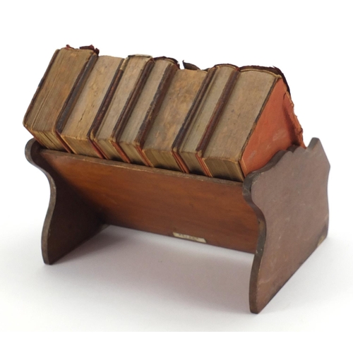 1009 - Miniature mahogany bookshelf housing eight books by Asprey of London, 20.5cm wide