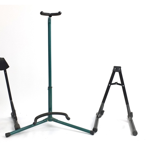 38 - Three folding metal guitar stands and an extendable green metal stand, the largest 75cm high