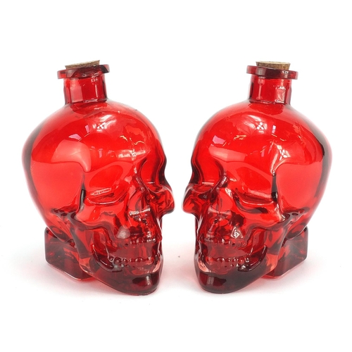 1855 - Pair of human skull design ruby glass bottles, 16.5cm high