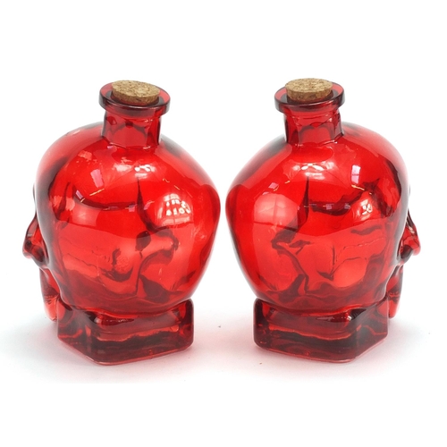 1855 - Pair of human skull design ruby glass bottles, 16.5cm high