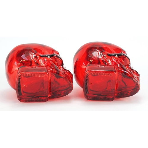 1855 - Pair of human skull design ruby glass bottles, 16.5cm high