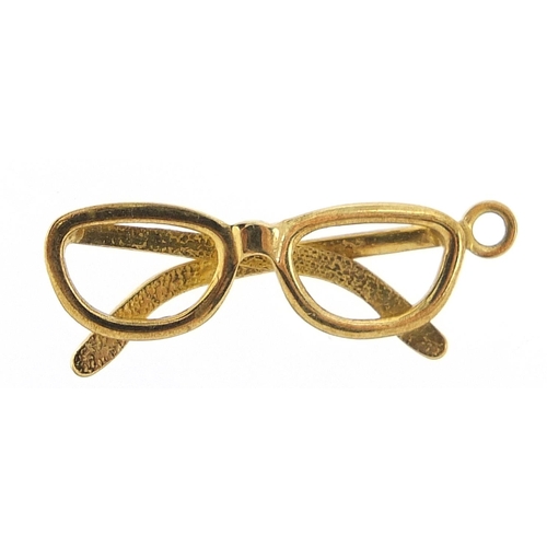 280 - Unmarked gold pair of spectacles charm, (tests as 9ct gold) 2.2cm high, 1.3g