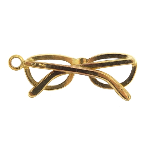 280 - Unmarked gold pair of spectacles charm, (tests as 9ct gold) 2.2cm high, 1.3g