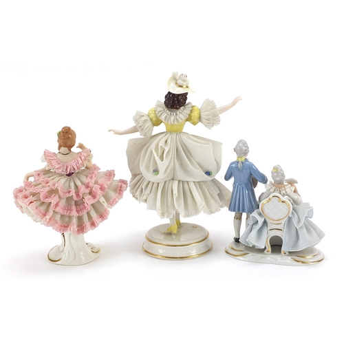 570 - Two Dresden porcelain lace figurines and a group of two lovers, the largest 17cm high