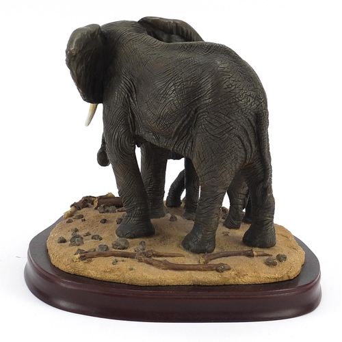 668 - Elephant and calf group raised on a hardwood stand, 22cm high