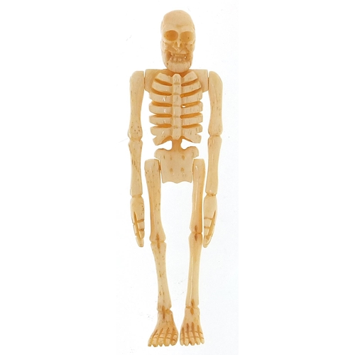 601 - Carved bone miniature coffin housing an articulated human skeleton, 11.5cm in length