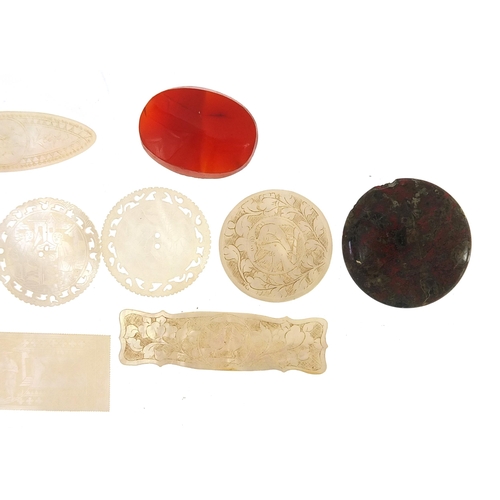 692 - Eleven Chinese carved mother of pearl gaming tokens and three polished stones, the largest 6cm in le... 