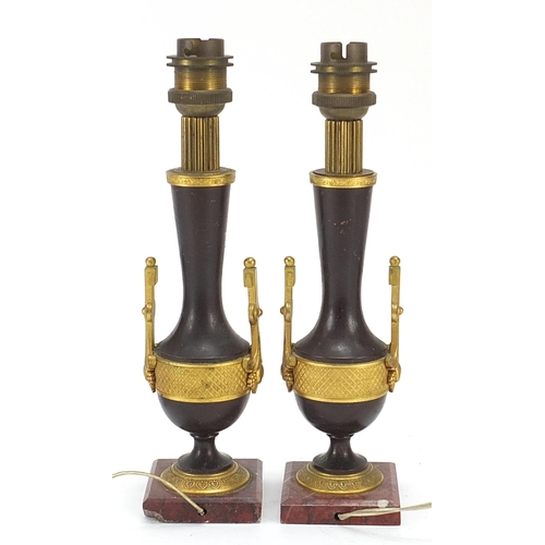 2 - Pair of French patinated bronze and ormolu candlesticks converted to table lamps, each raised on rou... 