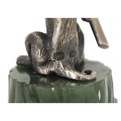 2227 - Novelty silver model of a seated gundog with ruby eyes, raised on a green jade tree stump, 8cm high,... 