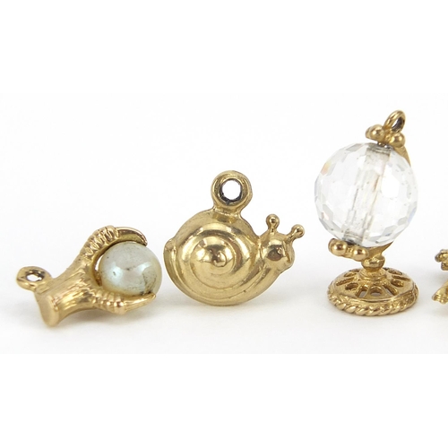 1820 - Five gold charms including crystal frog and globe and a dragon claw with pearl, the largest 1.5cm hi... 