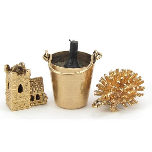 1666 - Three 9ct gold charms comprising opening church, hedgehog and Champagne ice bucket, the largest 2.4c... 