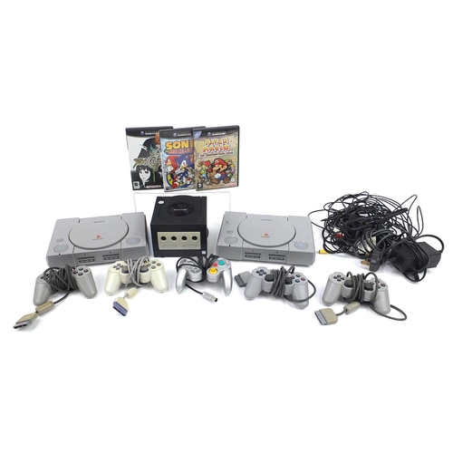 1523 - Two PlayStation 1 consoles with controllers and a Nintendo Game Cube console with controllers and ga... 