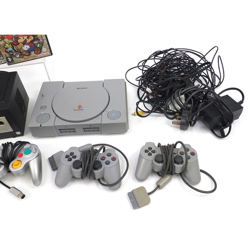 1523 - Two PlayStation 1 consoles with controllers and a Nintendo Game Cube console with controllers and ga... 