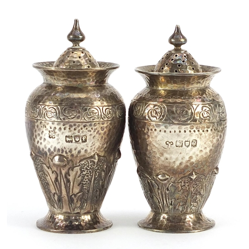 2262 - Pair of Arts & Crafts silver casters with engraved, planished and embossed decoration, indistinct ma... 