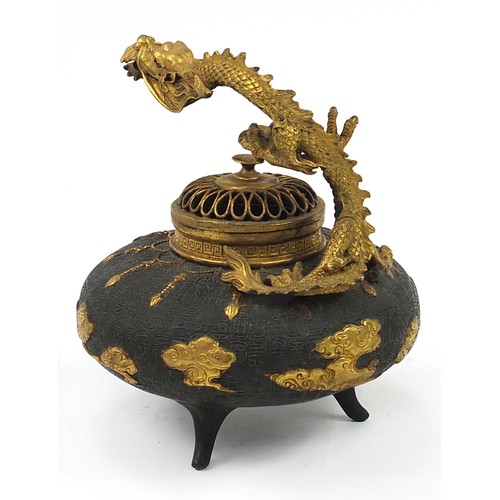 202 - Chinese partially gilt patinated bronze tripod incense burner with pierced lid and dragon handle, de... 