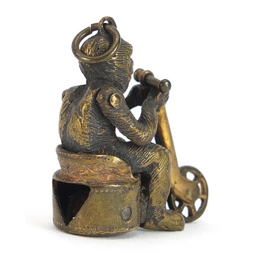 133 - Novelty early 20th century brass cigar cutter in the form of a monkey riding a bicycle, 3.5cm high