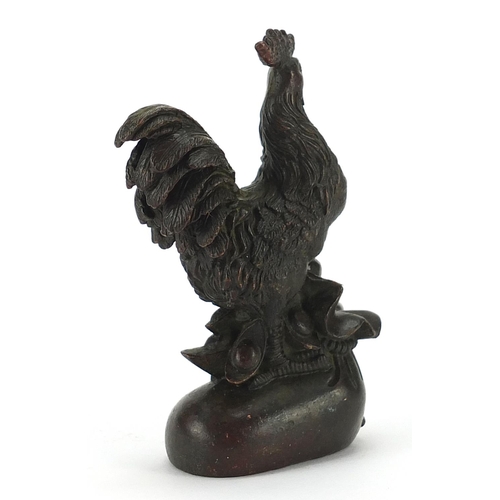 955 - Japanese patinated bronze rooster standing on a sack, impressed marks to the base, 9.5cm high