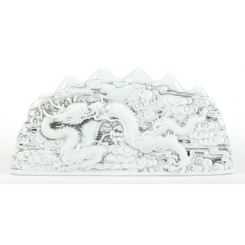 283 - Chinese blanc de chine porcelain scholar's brush rest decorated in relief with dragons amongst cloud... 