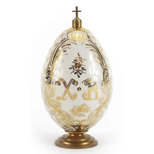 381 - Antique Russian porcelain Easter egg on metal stand with cross, the egg hand painted with panels of ... 