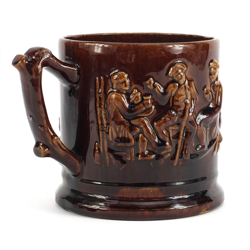 753 - Victorian treacle glaze mug decorated in relief with figures, 14cm high