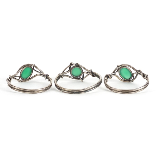 752 - Set of three white metal napkin rings set with green cabochon stones housed in a silk lined fitted b... 