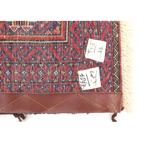 815 - Rectangular Persian red and blue ground rug having an all over geometric design, 172cm x 82cm