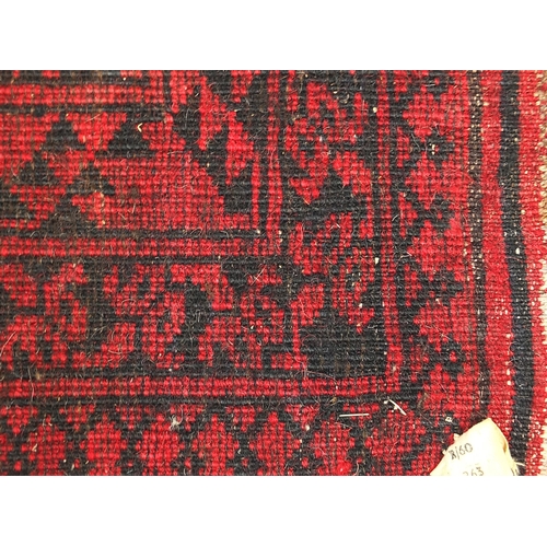 830 - Rectangular red and black ground rug having an all over geometric design, 125cm x 103cm