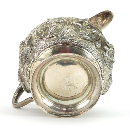 2245 - Indian unmarked silver cream jug with elephant head handle relief decorated with deities, 7.5cm high... 