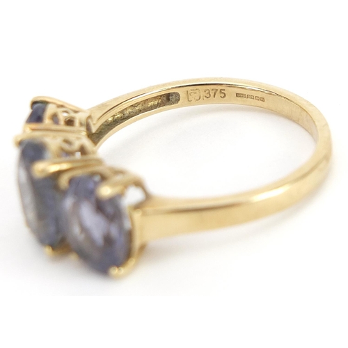 1756 - 9ct gold purple stone three stone ring, size O, 2.8g