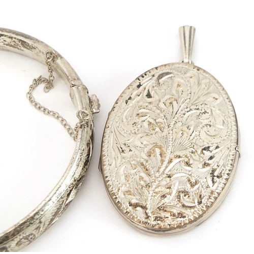 1999 - Two silver hinged bangles and a silver oval locket engraved with foliage, 62.3g