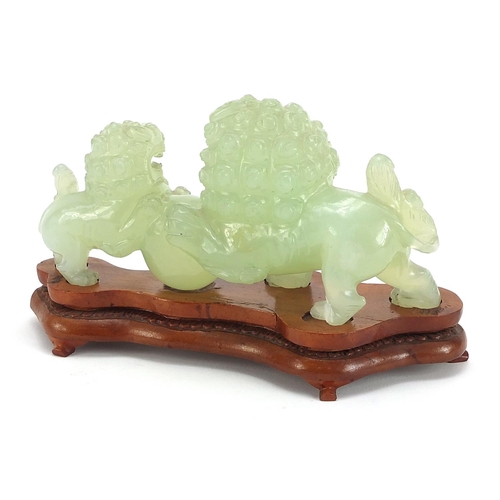 990 - Chinese green jadeite carving of two qilins raised on carved hardwood stand, 18cm in length