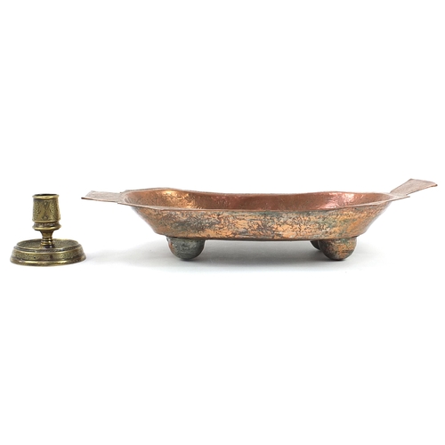 946 - Islamic brass candlestick and a copper four footed dish incised with wild animals and flowers, the l... 