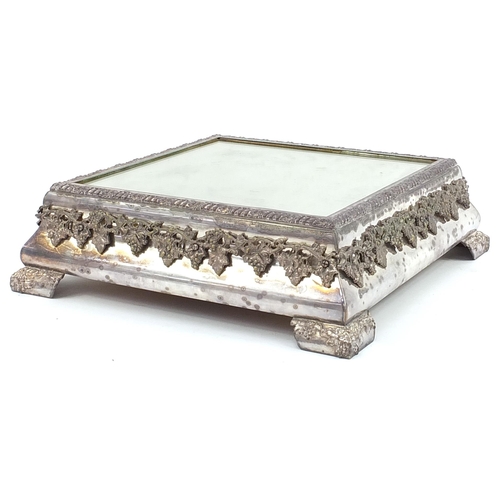 55 - Square silver plated mirrored cake stand relief decorated with grapes on a vine, housed in a painted... 