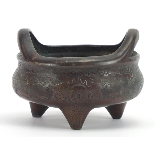 609 - Chinese patinated bronze tripod incense burner with twin handles, incised with dragons chasing a fla... 