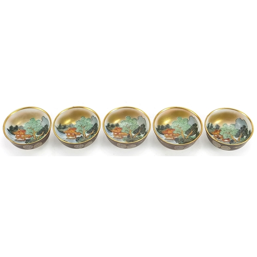 1117 - Five Japanese porcelain tea bowls hand painted with landscape scenes housed in a fitted case, each 5... 