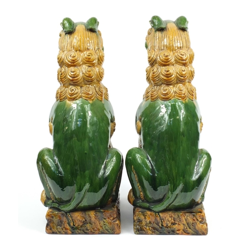 106 - Large pair of Chinese floor standing pottery seated lions having a sancai type glaze, each 59cm high