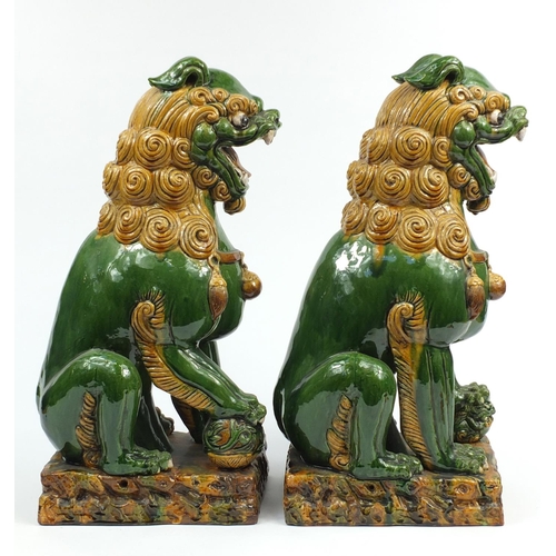 106 - Large pair of Chinese floor standing pottery seated lions having a sancai type glaze, each 59cm high