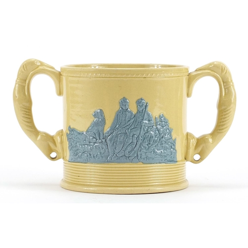 562 - Victorian twin handled cup decorated in relief with huntsmen and hounds, 22cm wide