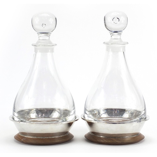 2123 - Pair of cut glass decanters with silver mounted oak stands by Simon J Beer London 1986, 27cm high