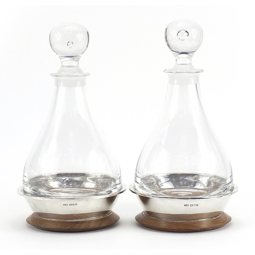 2123 - Pair of cut glass decanters with silver mounted oak stands by Simon J Beer London 1986, 27cm high