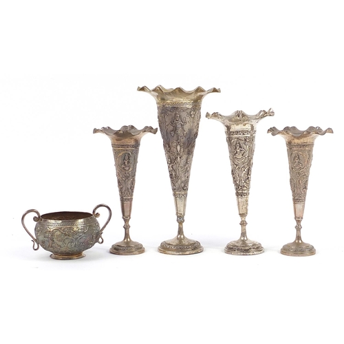 2136 - Four Indian white metal vases and sugar bowl with twin handles profusely embossed with deities, the ... 