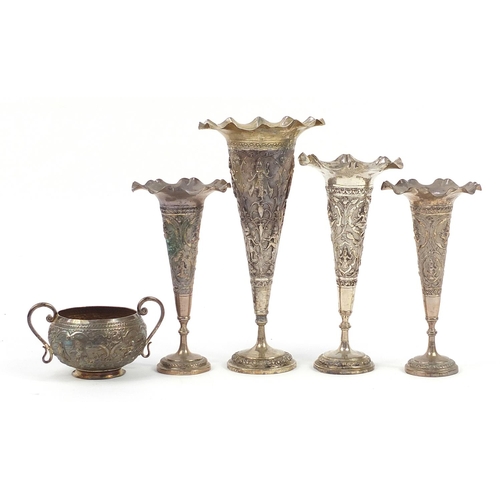 2136 - Four Indian white metal vases and sugar bowl with twin handles profusely embossed with deities, the ... 