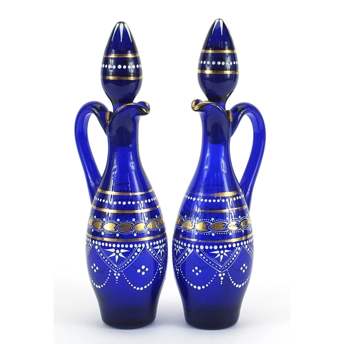 502 - Pair of blue glass oil and vinegar bottles hand painted with flowers, each 28cm high