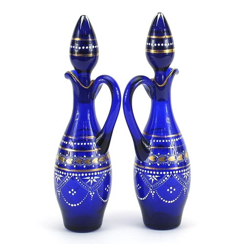 502 - Pair of blue glass oil and vinegar bottles hand painted with flowers, each 28cm high