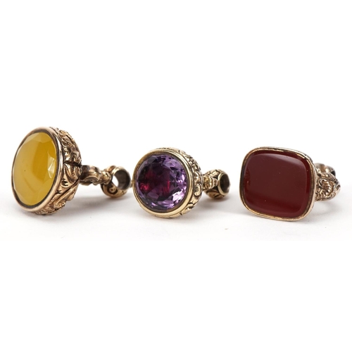 1417 - Three yellow metal fobs, one set with a carnelian, the largest 3.5cm high, 44.5g